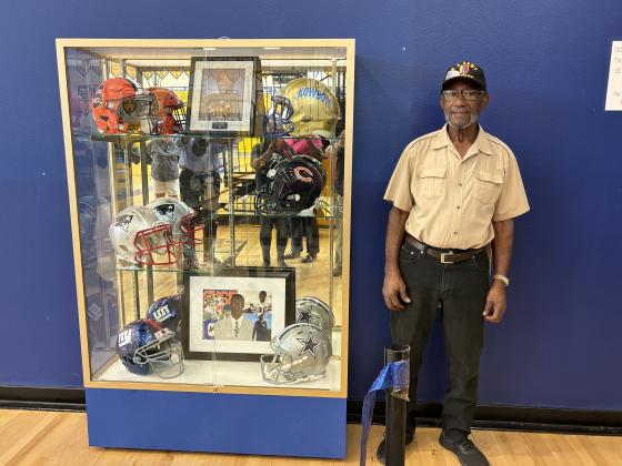 The Markus Paul Memorial -- complete with helmets of teams he played or worked for -- was unveiled Tuesday at Osceola High School, where he father, Isaiah Paul, was also honored. PHOTO/OSCEOLA HIGH SCHOOL